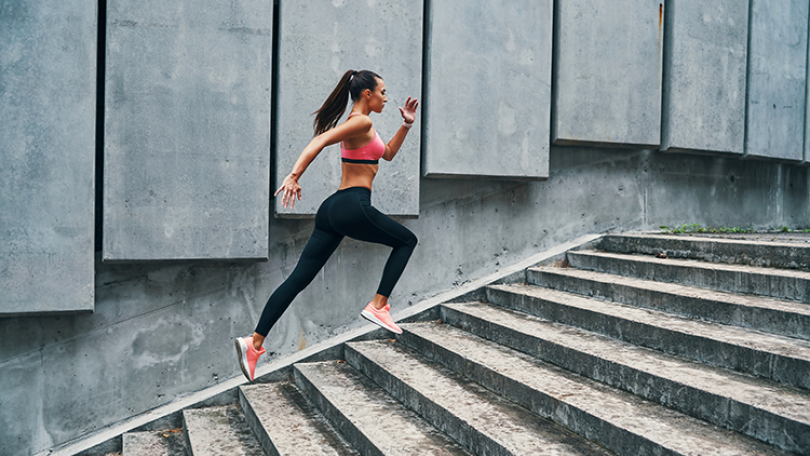 Eine Frau in Sportkleidung rennt eine Treppe hoch.